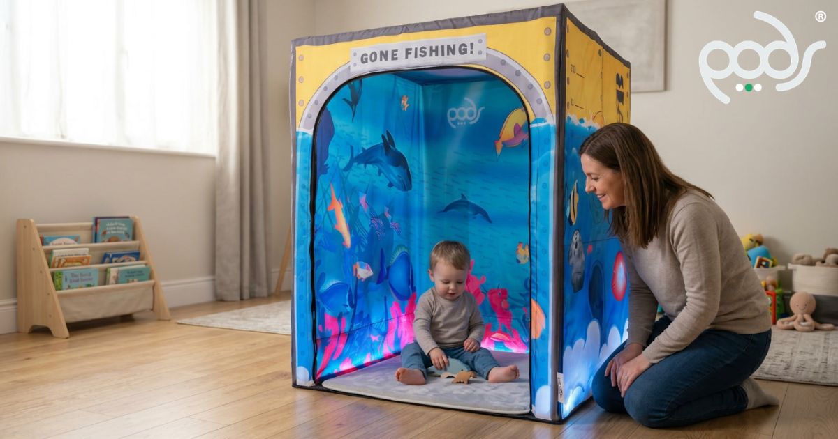 Toddler exploring inside a PODSgo Sub Aqua sensory play tent with a parent in a family playroom.